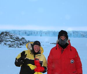 Two expeditioners with a large glacier in the background