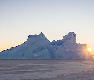 Sun rising alongside and iceberg