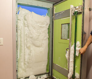 Inside the building looking out, external doorway completely covered with snow