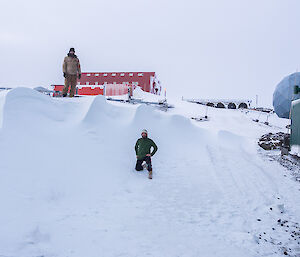 One expeditioner standing on top of the large snow drift the other at the base