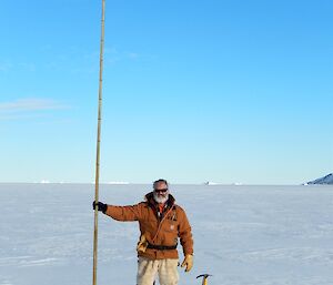 Expeditioner standing on sea ice holding a cane pole
