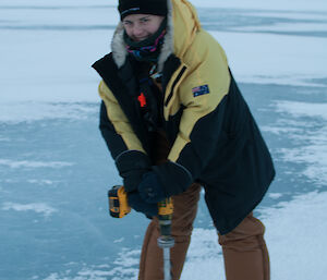Expeditioner drilling through a thick layer of ice