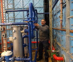 Expeditioner standing next to large tanks indoors