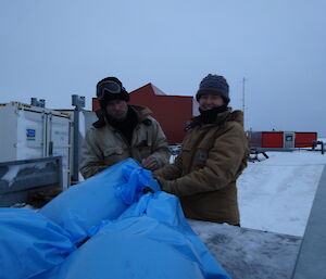 Two expeditioners standing at the end of a ute full of garbage bags