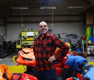 Expeditioner standing alongside quad bike with tools in hand