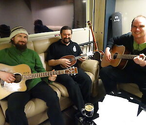 Three expeditioners sitting on lounges playing the guitars