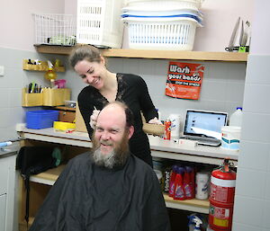 Expeditioner applying dye to another’s hair in the laundry