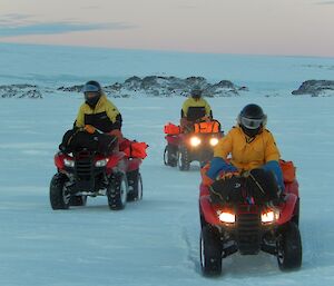 Three expeditioners riding quad bikes on the sea ice