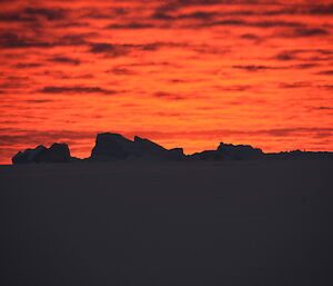 Bright red sunset with icebergs in the foreground