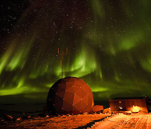 Bright green aurora above the satelite dome