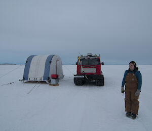 Expeditioner holding radio to her ear mobile science tent in background