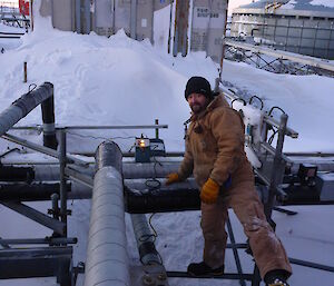 Expeditioner working on outside pipes connecting to buildings