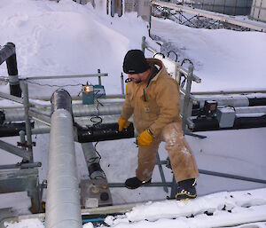 Expeditioner standing alongside numerous pipes leading to a building