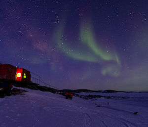 Night photo aurora over small red hut
