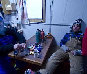 Two expeditioners covered in ice inside a hut