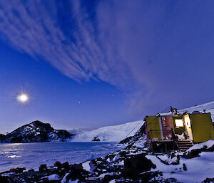Evening photo of yellow field hut with the icy plateau in the background