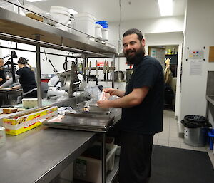 Expeditioner in the kitchen holding bacon