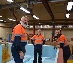 Three expeditioners standing in a shipping container lined with insulation