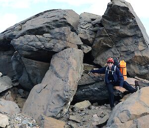 Expeditioner carrying a backpack standing next to large boulder