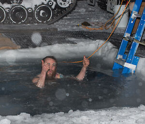 Expeditioner in icy water giving the thumbs up to the camera