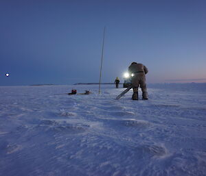 Expeditioner with chainsaw curring through thick sea ice