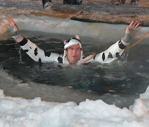 expeditioner in the icy water wearing a black and white cow onesie