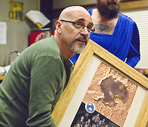 Expeditioner holds up a large framed photo