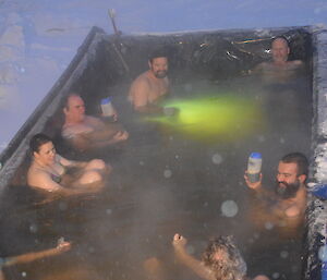 Expeditioners sitting in a large hot tub outside