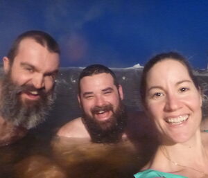 Three expeditioners sitting in an outdoor hot tub