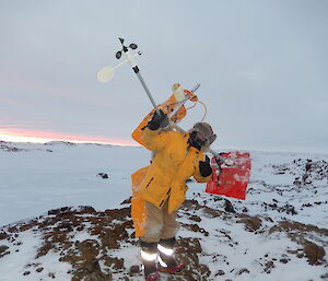 Expeditioner holding a small weather station in the field