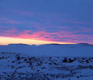 Red and pink sunset across the sea ice and island