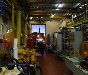 Four expeditioners inside the main power house giving directions to the JCB driver