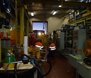 Large yellow engine being supported by two diesel mechanics