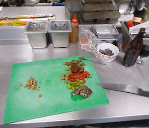 eggplant, capsicum, olives and other ingredients on chopping board in kitchen