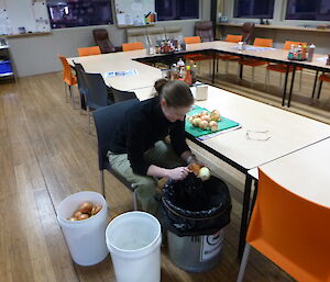 Expeditioner peeling a bucket of onions while sitting at the dinner table