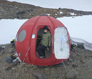 Expeditioner standing in the doorway of a hut in the shape of an apple