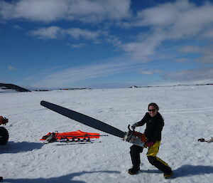 Expeditione posing for a photo, holding large chainsaw on the sea ice