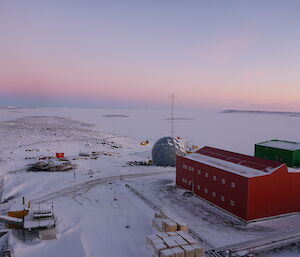 Aerial photo looking over station buildings, sea ice and a few islands during a sunset