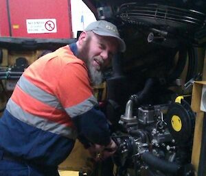 Expeditioner working under the engine of a large vehicle in the workshop