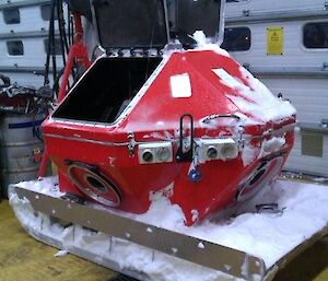 A small diesel powered genset inside positioned inside a large red weather proof case