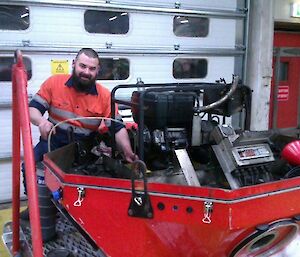 Expeditioner inside workshop working on a generator positioned inside a large red case