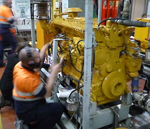 Expeditioner installing a large yellow engine
