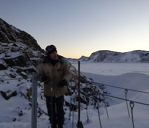 Expeditioner standing on a snow covered swing bridge