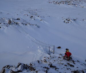 Aerial photo of three expeditioners working on a snow covered swing bridge