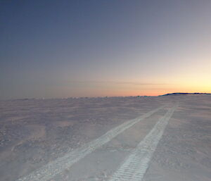 Hägglunds tracks on sea ice leading to a stunning soft sunrise