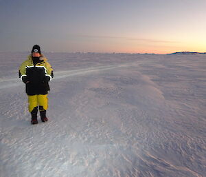 Expeditioner in yellow Antarctic clothing standing in the sea ice