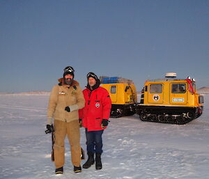 Two expeditioners standing on the sea ice looking at the stunning pink sunrise