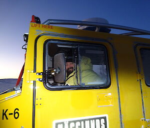 Expeditioner looking out the window of a yellow Hägglunds
