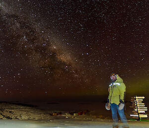 Night photo of an expeditioner standing beneath the stunning Milky Way in the sky