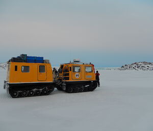 Yellow Hägglunds parked on the sea ice with the Sørsdal glacier in the background